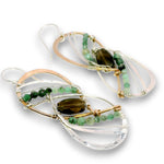 A pair of handmade dangle earrings featuring clear quartz crystal loops, green beads, a dark brown teardrop gemstone, and rose gold and silver wire wrapping on a white background.