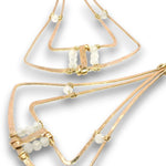 A close-up of a gold-toned geometric wire necklace with small white bead accents, shown on a plain white background.