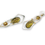 A pair of asymmetrical dangle earrings featuring olive green teardrop gemstones, small gold baroque pearls, and silver-toned and gold-toned wire wrap details, shown on a plain white background.