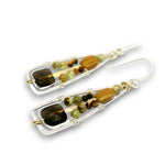 A pair of handmade dangle earrings featuring brown and olive green beads, set in silver-toned metal with small gold accents, shown against a plain white background.