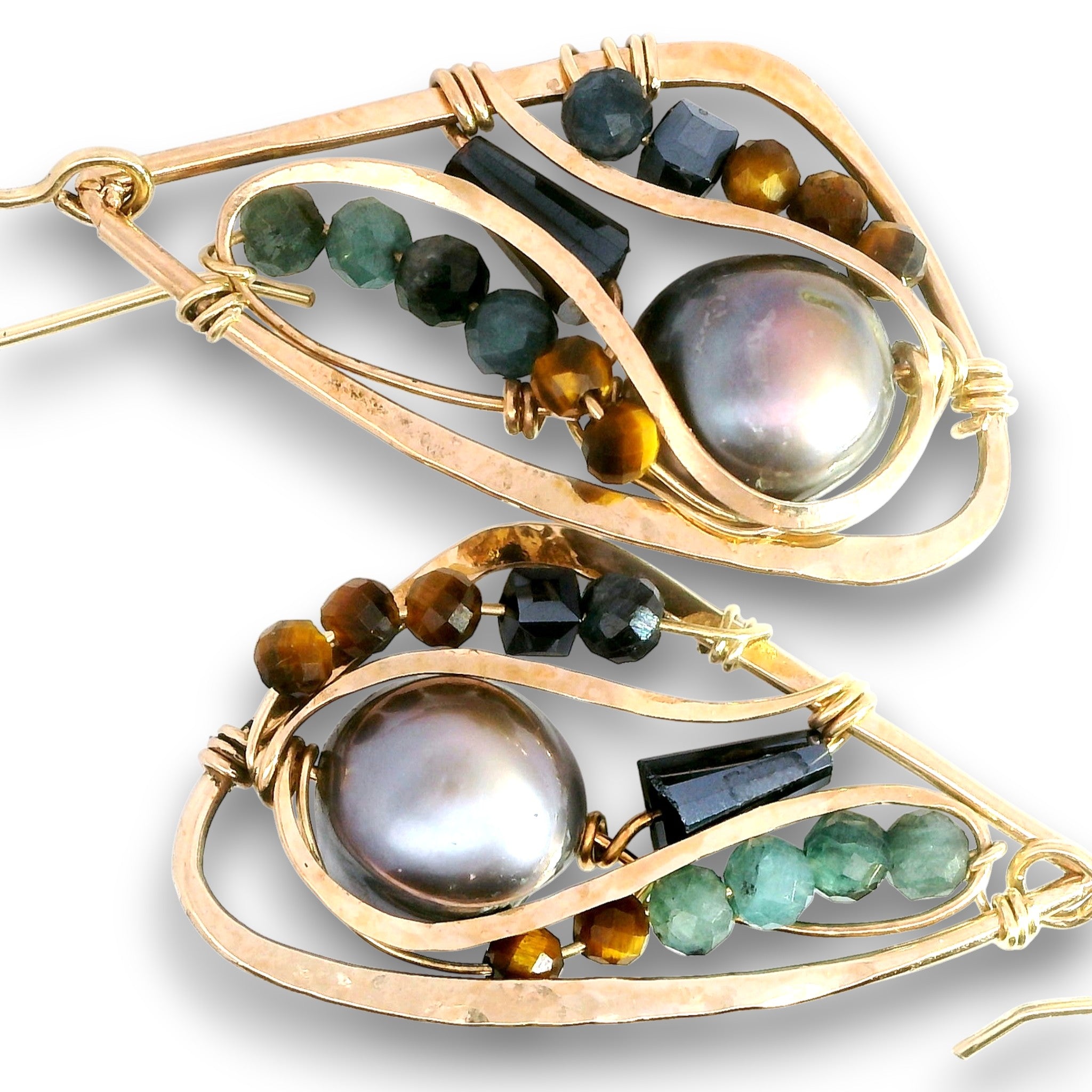 A pair of gold-toned teardrop-shaped earrings featuring a large iridescent pearl, faceted green and brown beads, and dark rectangular gemstones on a white background.
