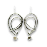 A pair of handmade silver dangle earrings featuring textured hammered metal loops, twisted wire details, and small rough natural stone drops, shown against a plain white background.