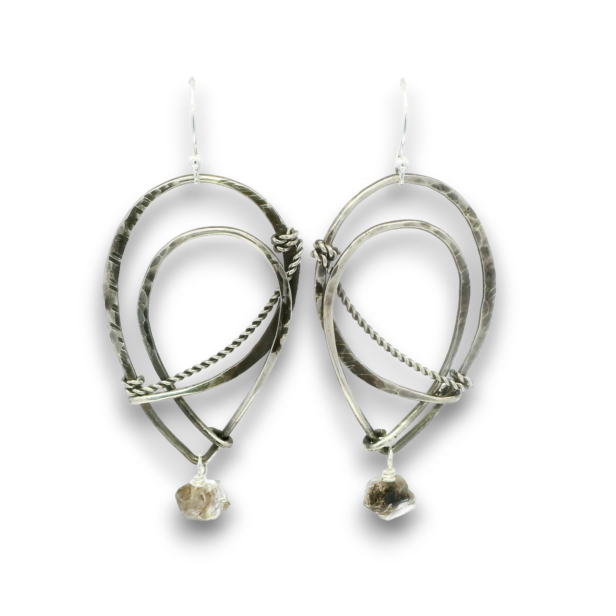 A pair of handmade silver dangle earrings featuring textured hammered metal loops, twisted wire details, and small rough natural stone drops, shown against a plain white background.