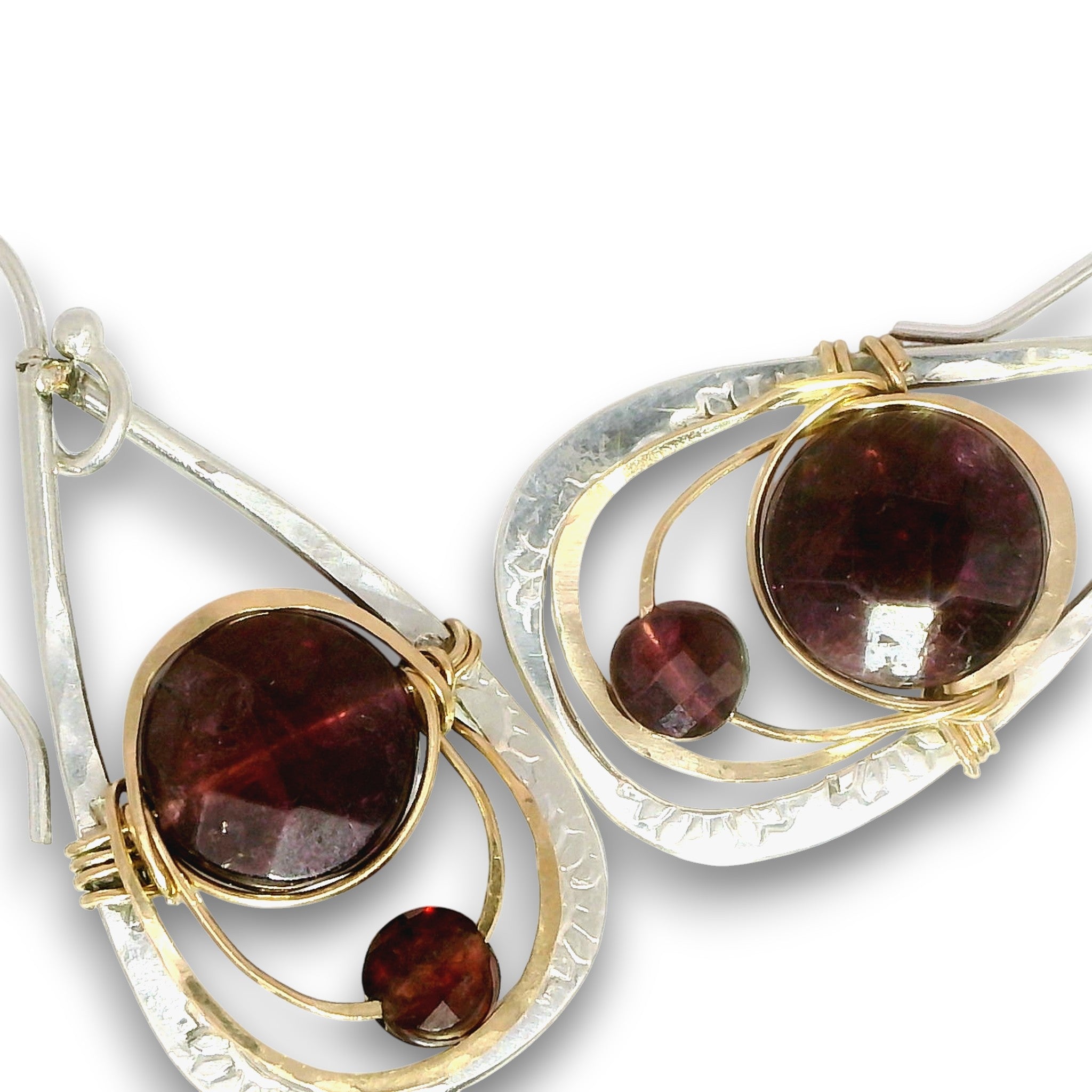 A pair of teardrop-shaped dangle earrings featuring large oval dark red garnet gemstones and smaller round garnet beads, set in a mix of silver and gold-toned metal wires, on a plain white background.