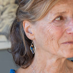 A pair of sterling silver mini diamond earrings featuring rust colored fresh water pearls, golden crystals, blue crystal drops, and lapis gemstones