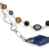 A diamond lapis gemstone is bezel set into sterling silver with handmade hammered link chain with rust and purple colored fresh water pearls necklace