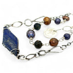 A diamond lapis gemstone is bezel set into sterling silver with handmade hammered link chain with rust and purple colored fresh water pearls necklace