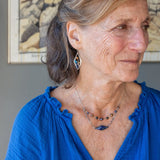 A diamond lapis gemstone is bezel set into sterling silver with handmade hammered link chain with rust and purple colored fresh water pearls necklace