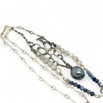 A sterling silver necklace with a handmade prong pendant featuring a deep blue sodalite natural gemstone, micro faceted sodalite and labradorite gemstones, and a lustrous gray blue fresh water pearl, connected to an oxidized link chain.