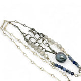A sterling silver necklace with a handmade prong pendant featuring a deep blue sodalite natural gemstone, micro faceted sodalite and labradorite gemstones, and a lustrous gray blue fresh water pearl, connected to an oxidized link chain.
