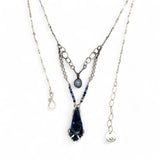 A sterling silver necklace with a handmade prong pendant featuring a deep blue sodalite natural gemstone, micro faceted sodalite and labradorite gemstones, and a lustrous gray blue fresh water pearl, connected to an oxidized link chain.