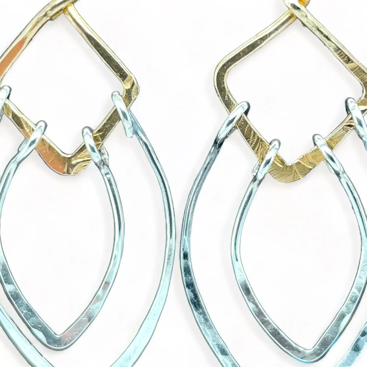 Sterling silver double teardrops swinging from stamped brass diamonds, all hanging from a braided brass link