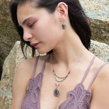 Larvikite and pink tourmaline gemstones are held within a sterling silver floral stamped drop pendant held on a layered chain made up of oxidized sterling silver textured and bright sterling tube chains necklace