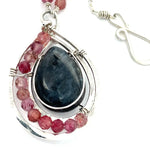 Larvikite and pink tourmaline gemstones are held within a sterling silver floral stamped drop pendant held on a layered chain made up of oxidized sterling silver textured and bright sterling tube chains necklace