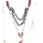 Larvikite and pink tourmaline gemstones are held within a sterling silver floral stamped drop pendant held on a layered chain made up of oxidized sterling silver textured and bright sterling tube chains necklace