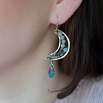 Handmade brass moon earrings with labradorite, iolite, pyrite, and crystal gemstones inside with a blue faceted crystal drop hanging from the bottom