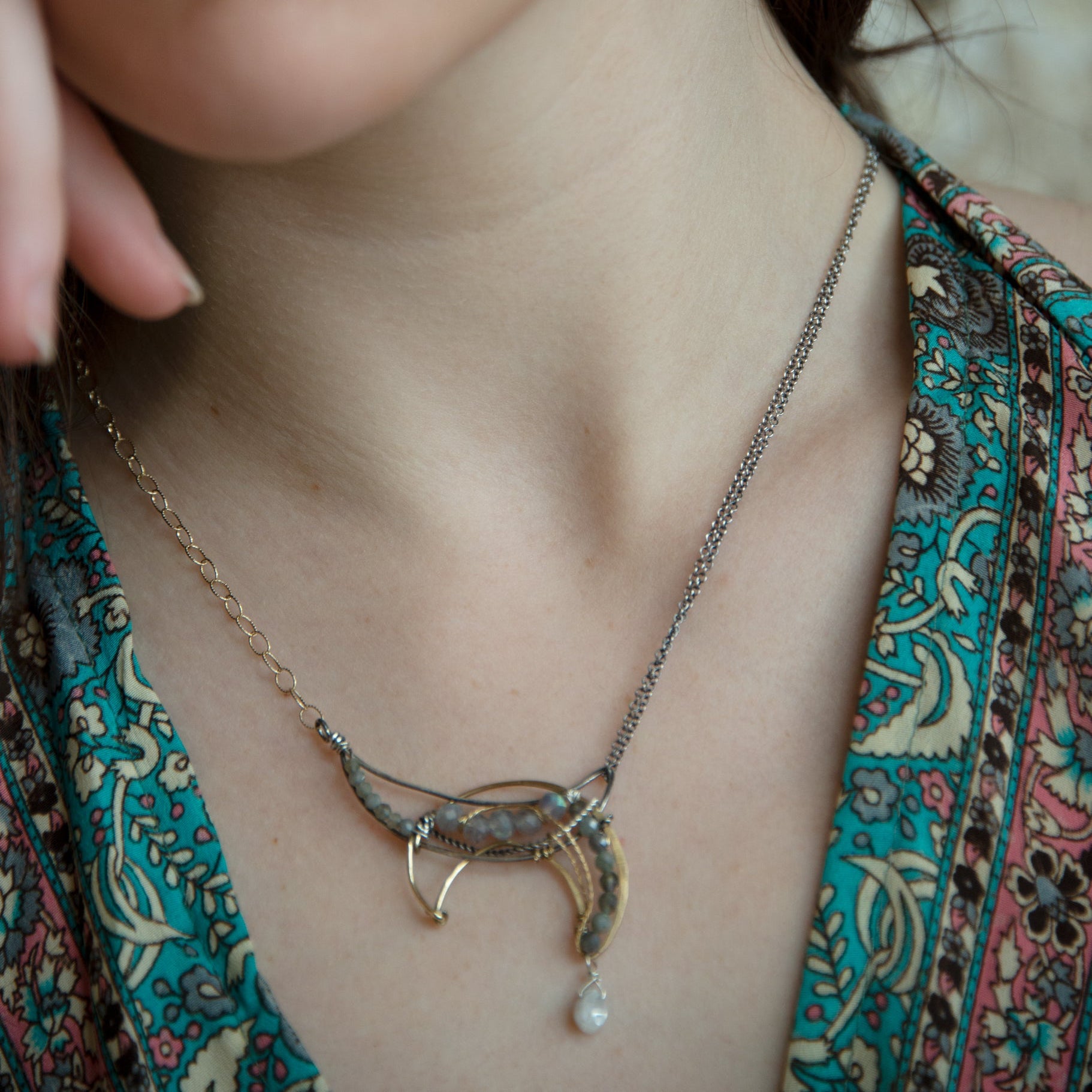 A necklace with a silver and brass moon eclipse design, featuring faceted labradorite gemstones and a single white sapphire drop, oxidized sterling silver and brass twist wires, gold filled texture chain on one side and double sterling silver chain on the other side