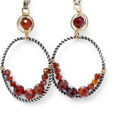 A pair of twisted oxidized sterling silver hoop earrings with garnet gemstone accents and faceted hessonite garnets on gold filled wire