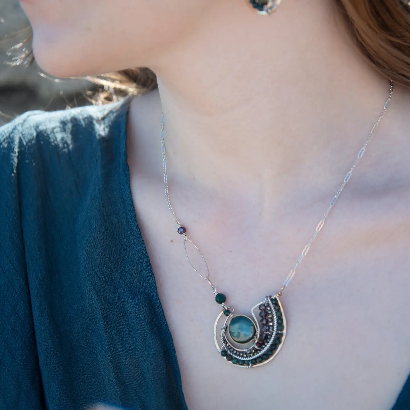 A  hand formed bronze pendant necklace with green fresh water pearl coin, bloodstone faceted gems, crystal, and pyrite on a sterling silver delicate chain with sparkly rose quartz links
