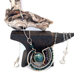 A  hand formed bronze pendant necklace with green fresh water pearl coin, bloodstone faceted gems, crystal, and pyrite on a sterling silver delicate chain with sparkly rose quartz links