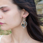 Crystal, emerald, and opal gemstones vein between layers of brass wire inside a sterling silver leaf shaped earring