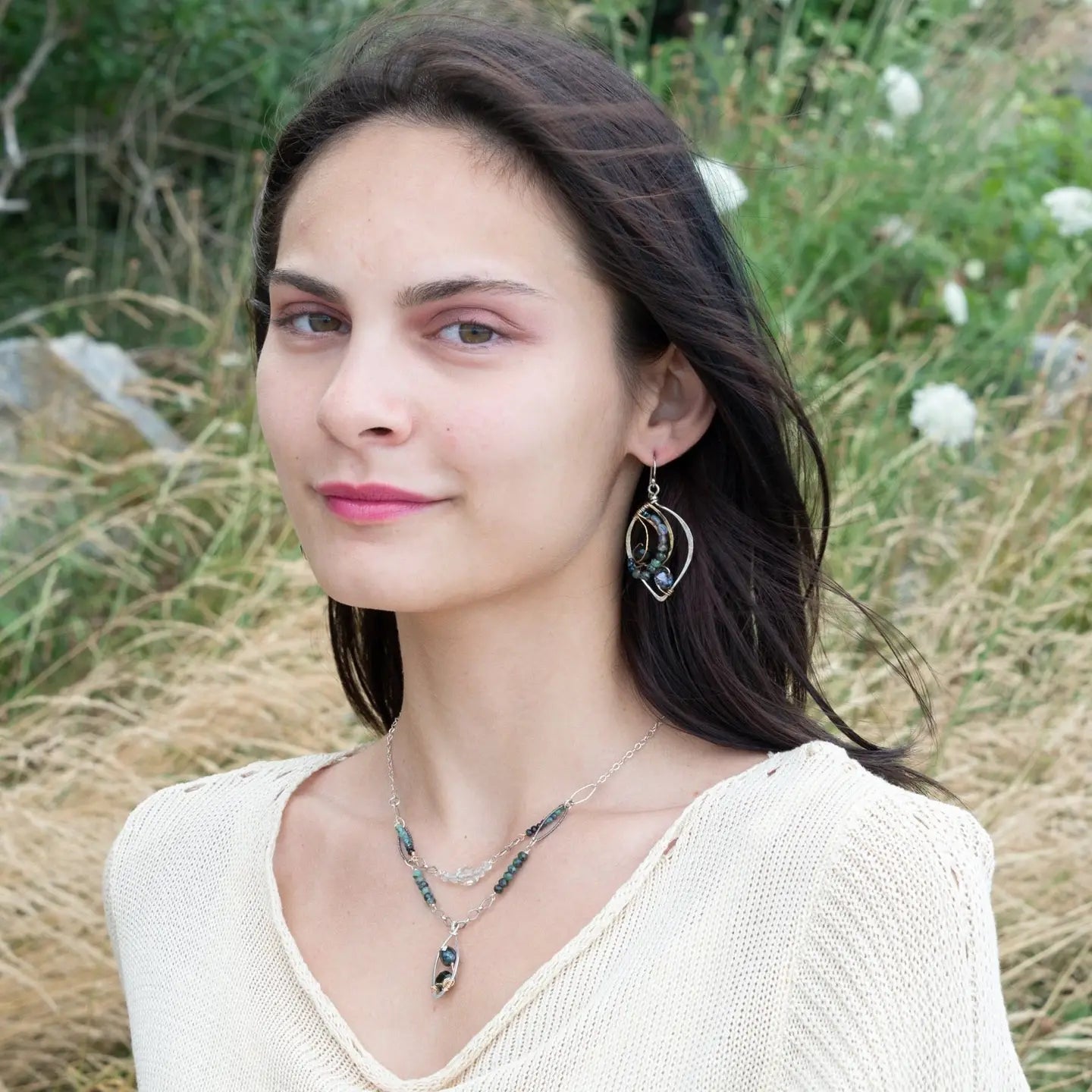 Crystal, emerald, and opal gemstones vein between layers of brass wire inside a sterling silver leaf shaped earring