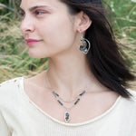 Crystal, emerald, and opal gemstones vein between layers of brass wire inside a sterling silver leaf shaped earring