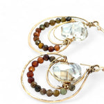 A pair of bronze hoop earrings with ombre micro faceted hessonite gemstones, inlaid in the hoops, in shades of rust and olive.