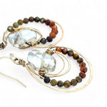 A pair of bronze hoop earrings with ombre micro faceted hessonite gemstones, inlaid in the hoops, in shades of rust and olive.