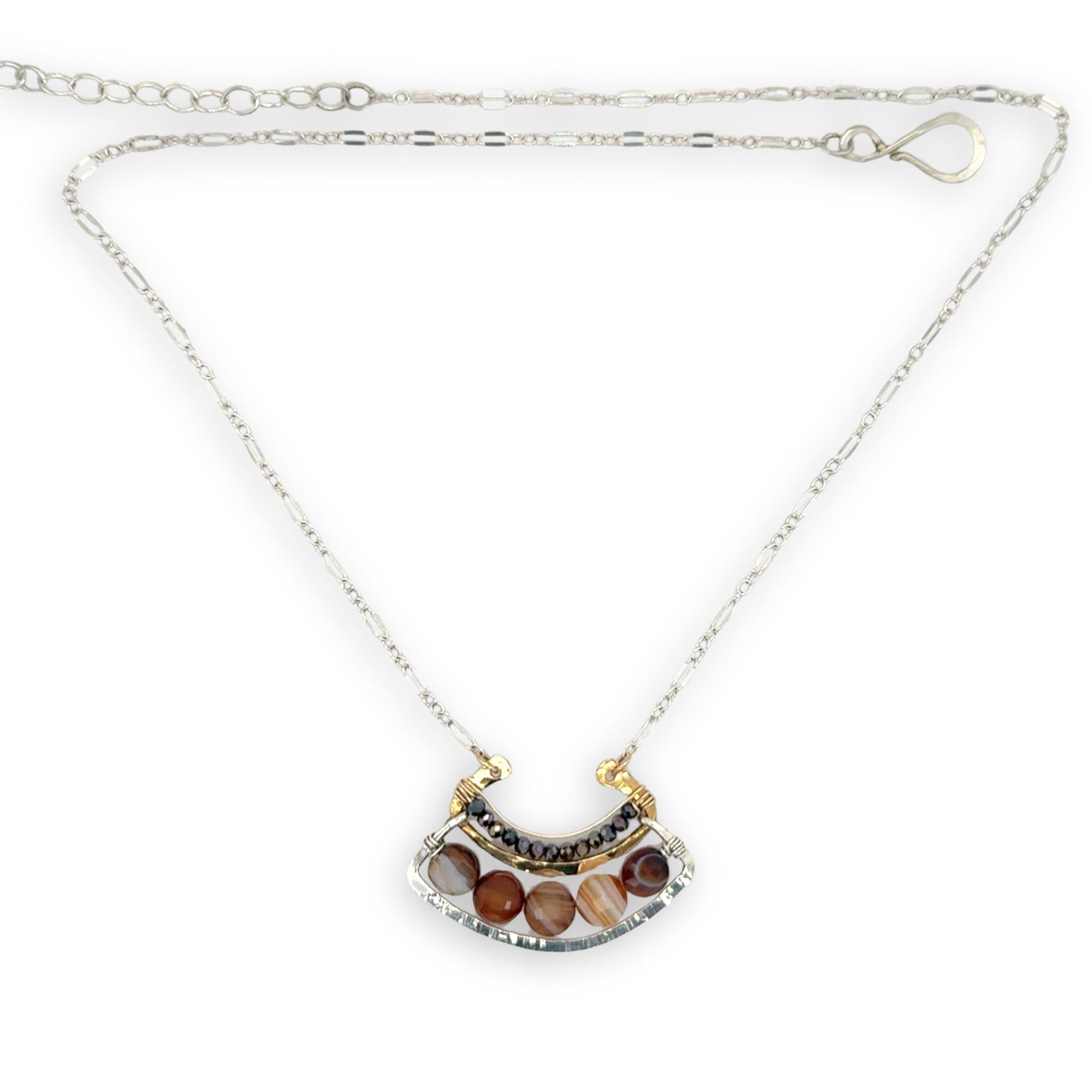Brown striped agate coins line the inside of a sterling silver and brass fan shaped pendant necklace with pyrite and gold fill accents