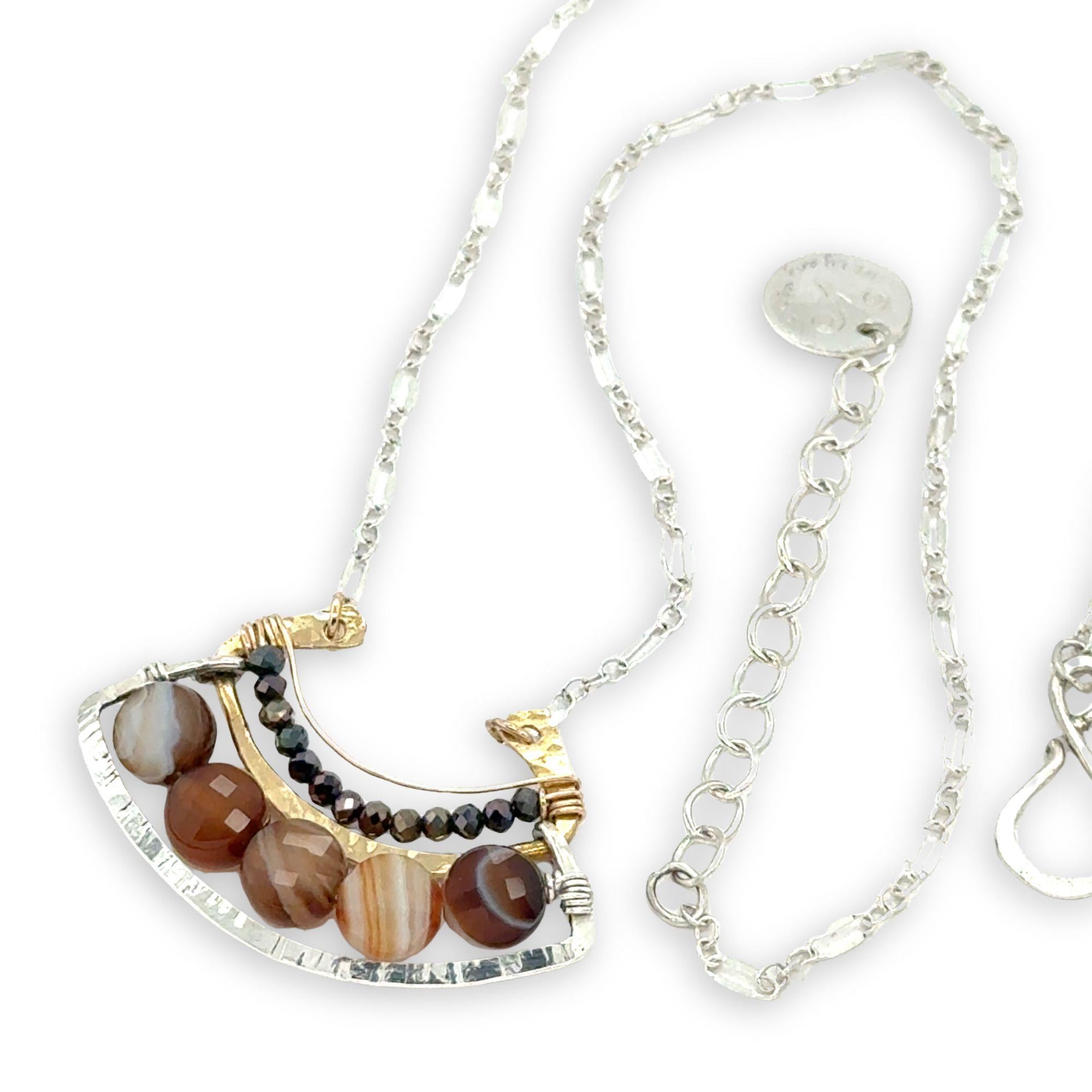 Brown striped agate coins line the inside of a sterling silver and brass fan shaped pendant necklace with pyrite and gold fill accents