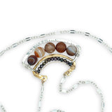 Brown striped agate coins line the inside of a sterling silver and brass fan shaped pendant necklace with pyrite and gold fill accents