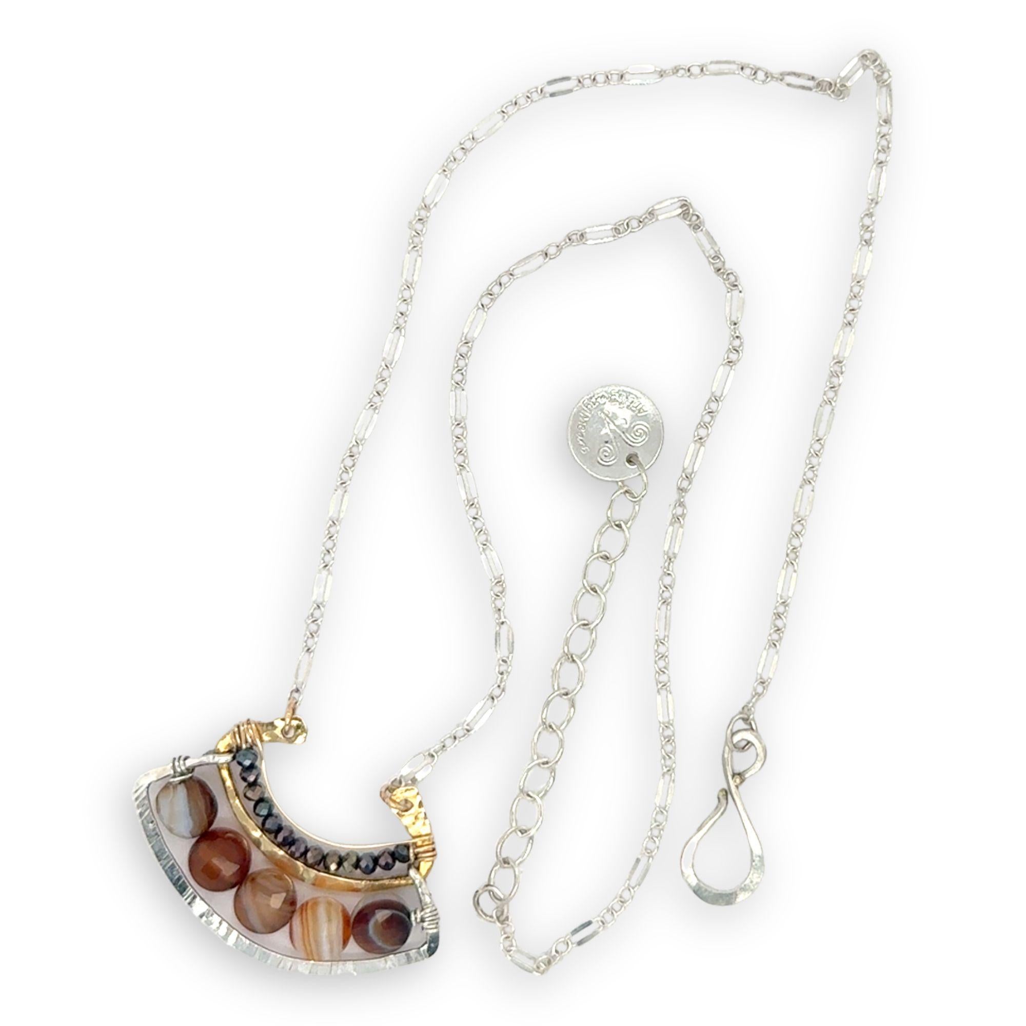 Brown striped agate coins line the inside of a sterling silver and brass fan shaped pendant necklace with pyrite and gold fill accents
