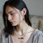 A double strand necklace with a geometric design, featuring fluorite and iolite faceted gemstones, hammered sterling silver, textured sterling silver links and handmade brass rings