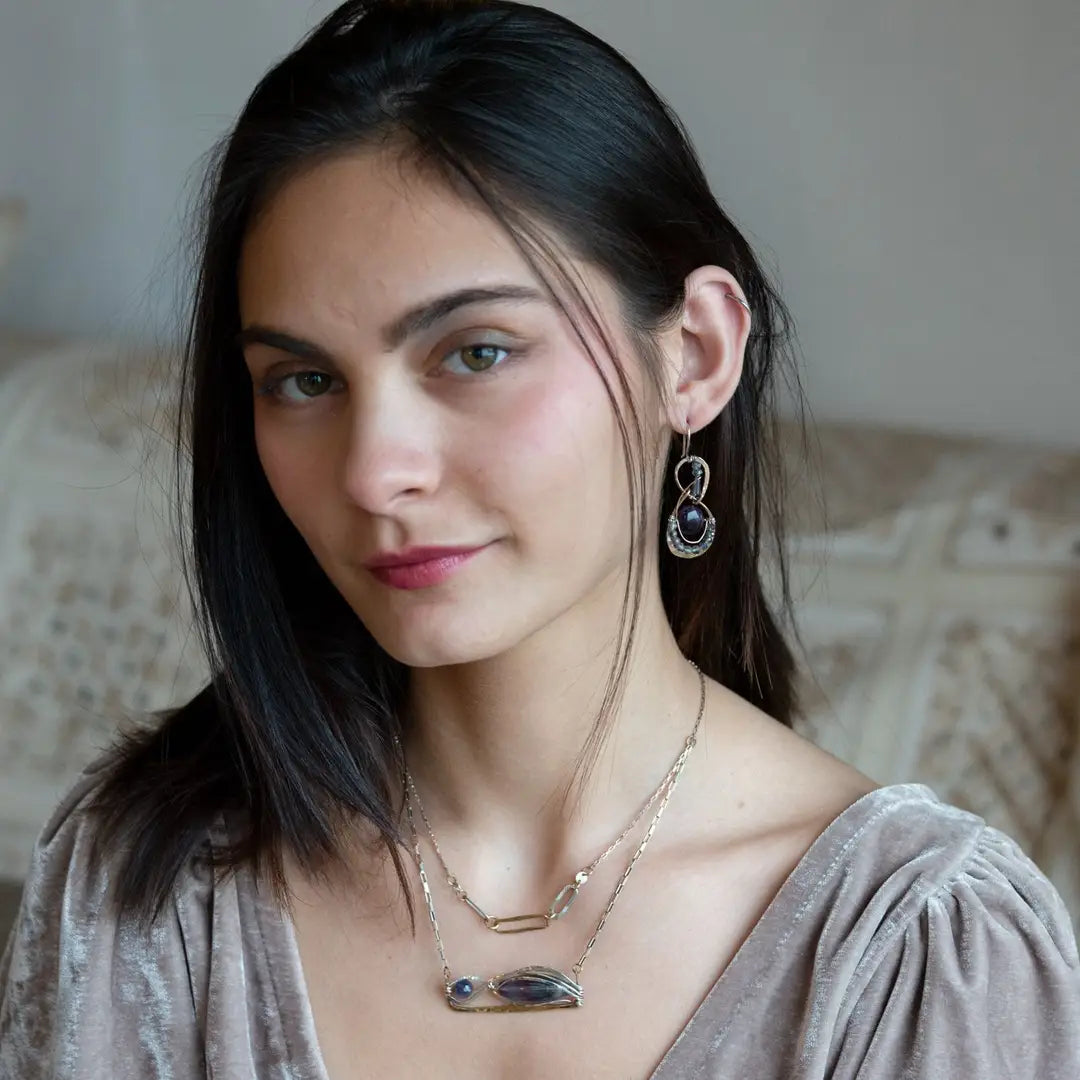 A double strand necklace with a geometric design, featuring fluorite and iolite faceted gemstones, hammered sterling silver, textured sterling silver links and handmade brass rings