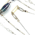 A double strand necklace with a geometric design, featuring fluorite and iolite faceted gemstones, hammered sterling silver, textured sterling silver links and handmade brass rings