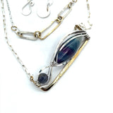 A double strand necklace with a geometric design, featuring fluorite and iolite faceted gemstones, hammered sterling silver, textured sterling silver links and handmade brass rings