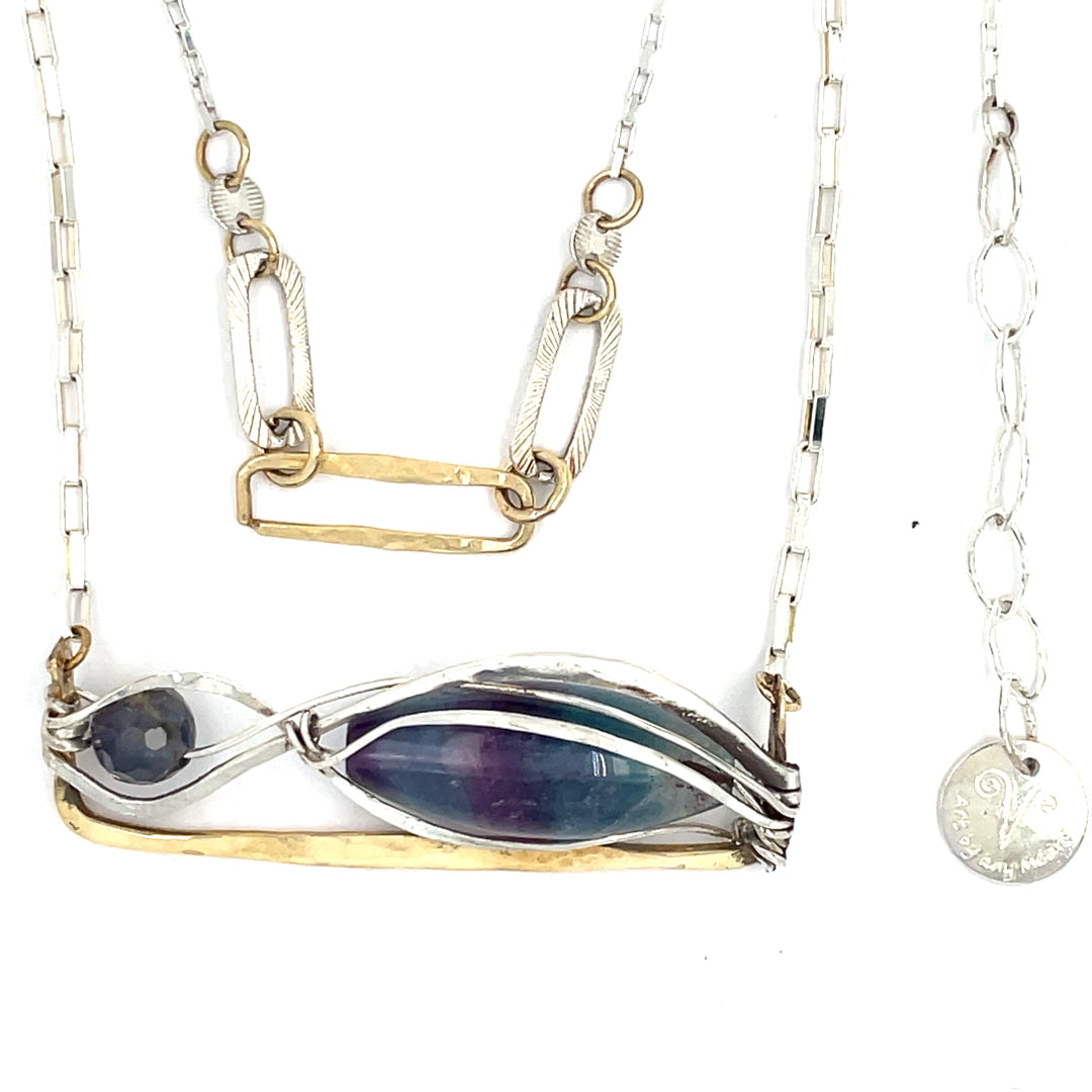 A double strand necklace with a geometric design, featuring fluorite and iolite faceted gemstones, hammered sterling silver, textured sterling silver links and handmade brass rings