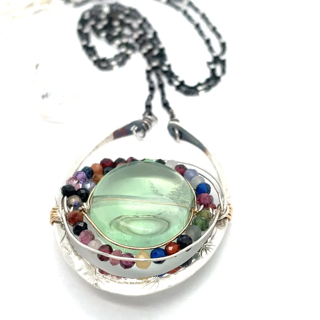 A sterling silver oval pendant necklace with a green fluorite smooth coin and micro faceted mixed gemstones, featuring an oxidized sterling silver dot chain 
