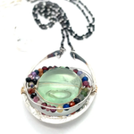 A sterling silver oval pendant necklace with a green fluorite smooth coin and micro faceted mixed gemstones, featuring an oxidized sterling silver dot chain 
