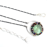 A sterling silver oval pendant necklace with a green fluorite smooth coin and micro faceted mixed gemstones, featuring an oxidized sterling silver dot chain 