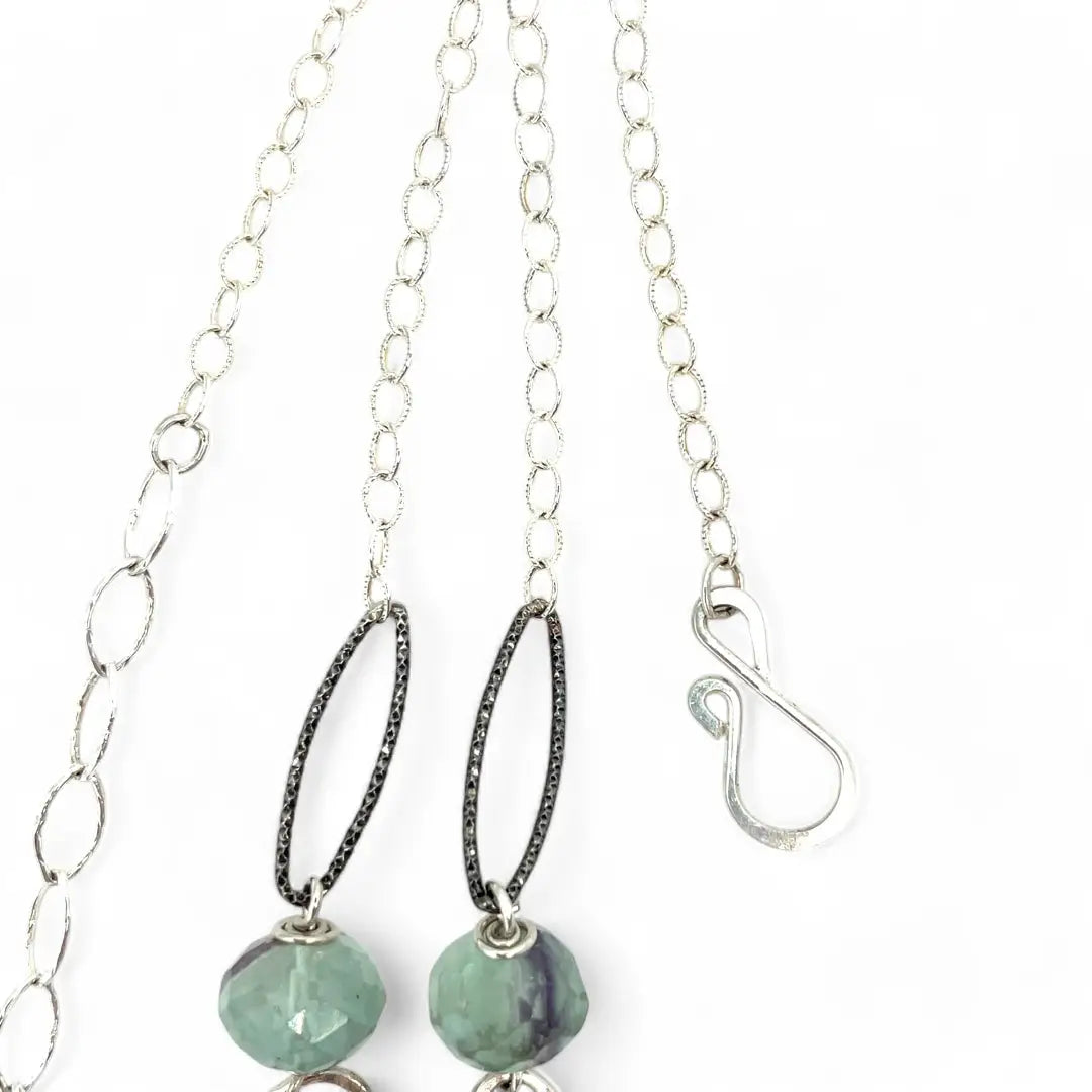 Purple and green faceted fluorite spheres are held within handmade hammered sterling silver oval and teardrop link, topped off with a delicate sterling silver chain necklace