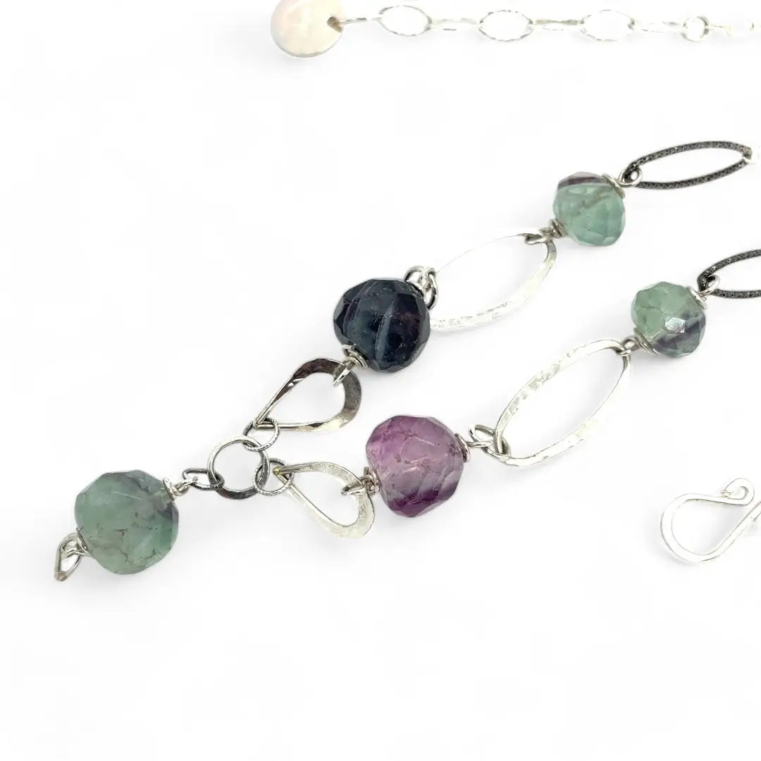 Purple and green faceted fluorite spheres are held within handmade hammered sterling silver oval and teardrop link, topped off with a delicate sterling silver chain necklace