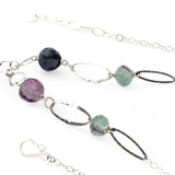 Purple and green faceted fluorite spheres are held within handmade hammered sterling silver oval and teardrop link, topped off with a delicate sterling silver chain necklace