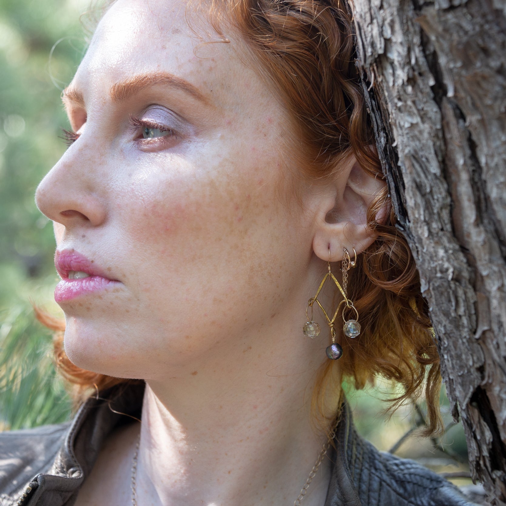A pair of brass chandelier earrings with champagne color crystal bubbles and peacock blue gray fresh water pearls.