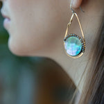 Iridescent abalone shell coins are surrounded by mauve moonstone gems within bronze teardrop earrings