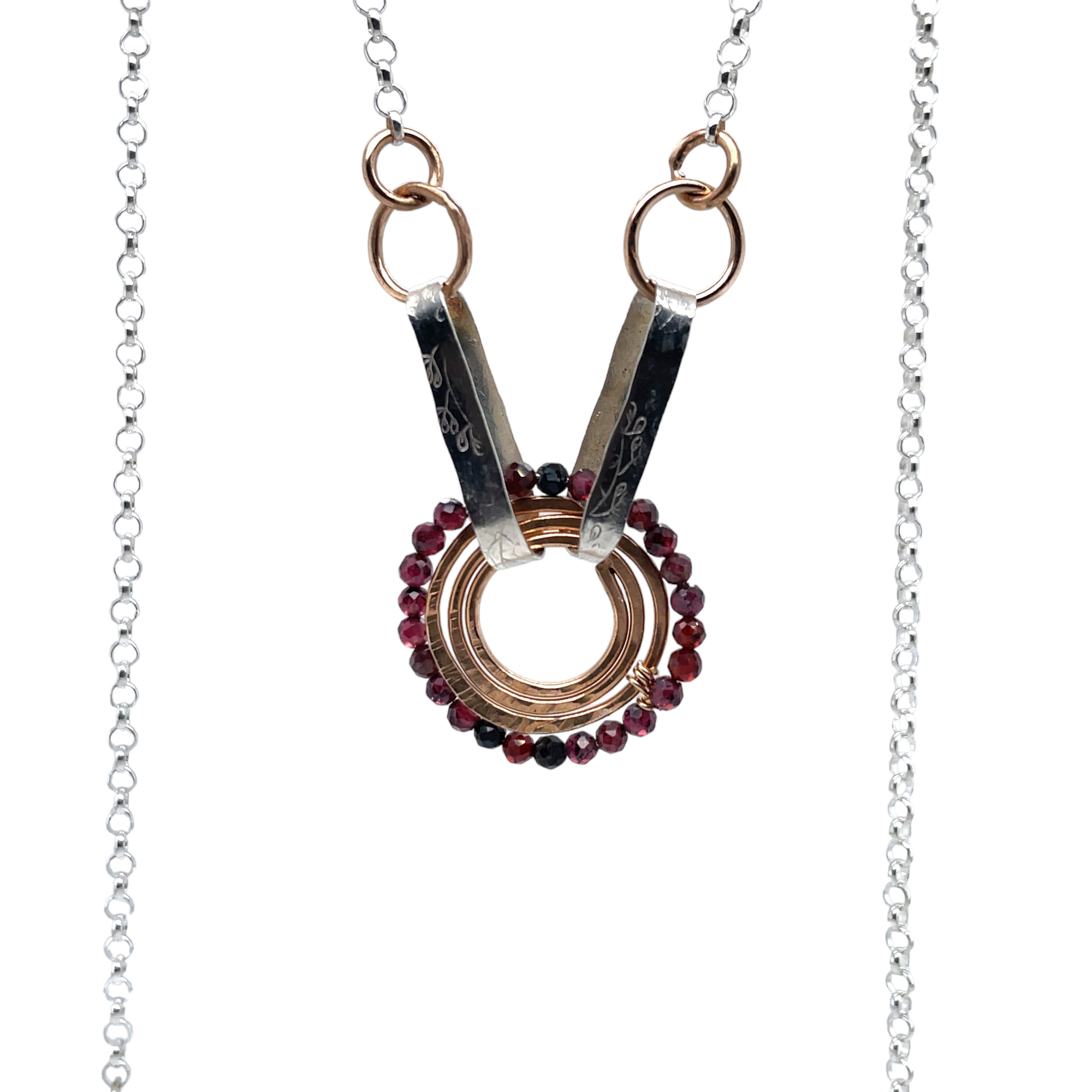 a bronze coil hammered pendant with garnet gemstones held from handmade hammered floral stamped oval links on sterling silver rolo chain necklace