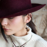 Sterling silver hammered hoops holding onto layers of bronze hammered wire wrapping a faceted garnet gemstone with a rich red fresh water pearl dangle earring