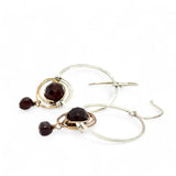 Sterling silver hammered hoops holding onto layers of bronze hammered wire wrapping a faceted garnet gemstone with a rich red fresh water pearl dangle earring