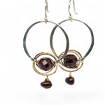Sterling silver hammered hoops holding onto layers of bronze hammered wire wrapping a faceted garnet gemstone with a rich red fresh water pearl dangle earring